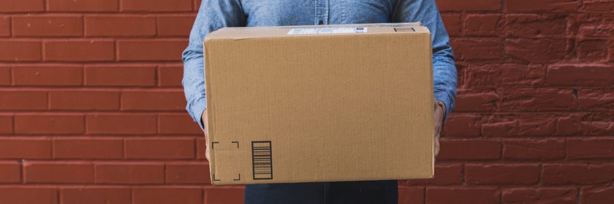 man-holding-shipping-box-on-red-brick